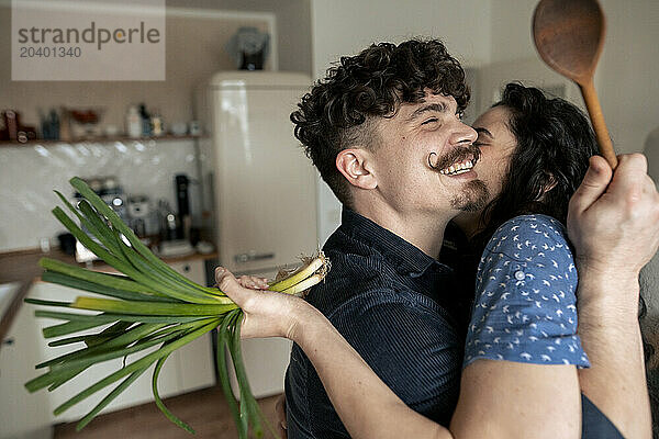 Happy couple embracing in kitchen at home