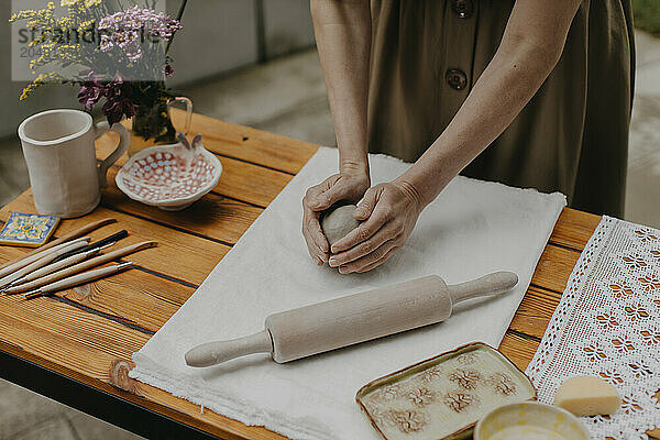 Woman kneading clay on white cloth at back yard