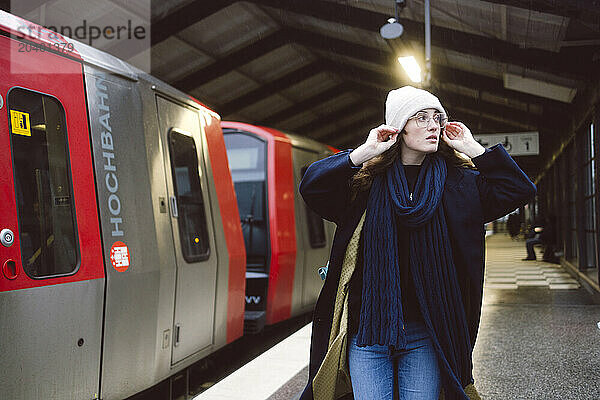 Beautiful woman wearing knit hat walking by train at station