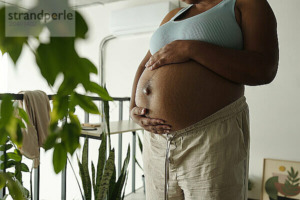 Pregnant woman touching belly at home