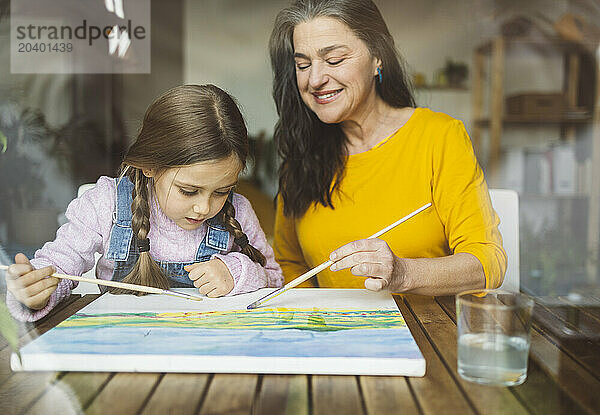 Grandmother and granddaughter painting together at table