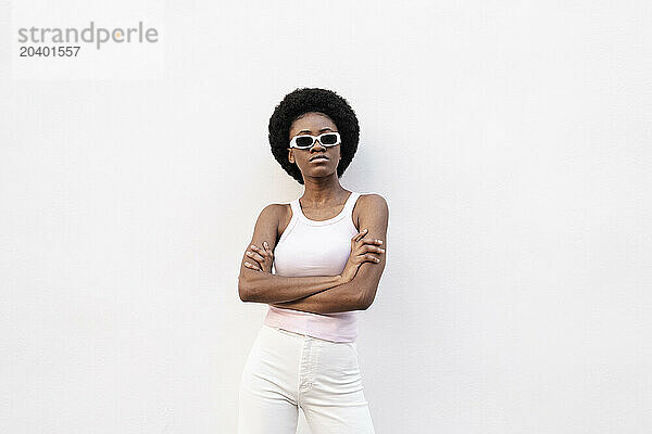 Fashionable Afro woman standing with arms crossed against white background