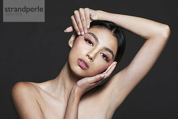 Beautiful young naked woman with make-up against grey background