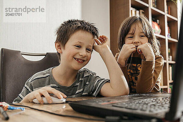 Happy brothers surfing net on laptop at home