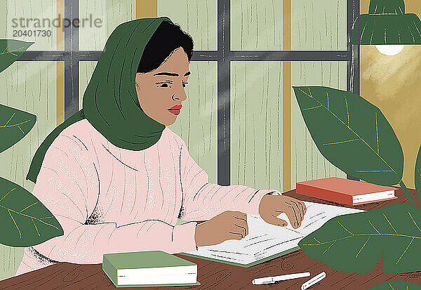 Woman wearing hijab reading book at home