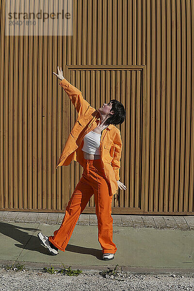 Woman in orange casuals dancing on sunny day