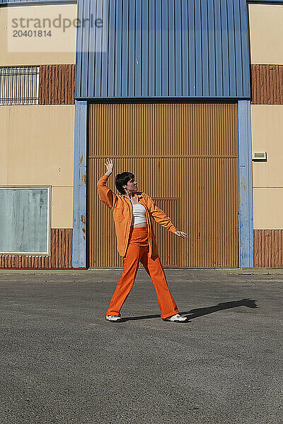 Woman dancing in front of building on sunny day