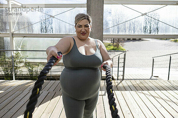 Curvy young woman exercising with rope at park