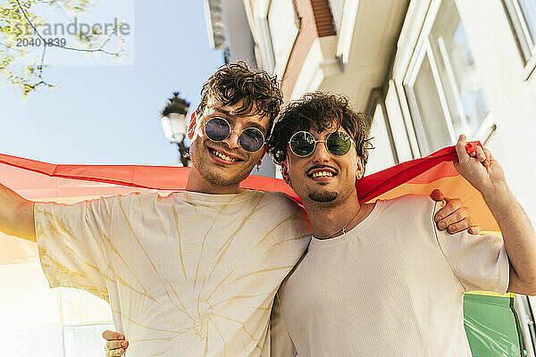 Smiling gay couple holding rainbow flag at gay pride parade