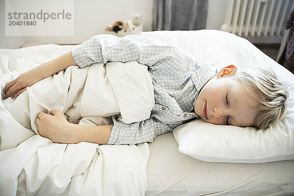 Boy wearing pajamas and sleeping on bed at home