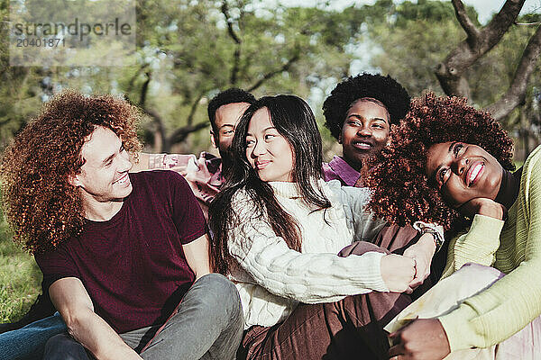 Happy multiracial friends sitting together at park