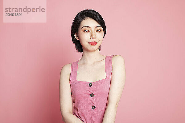 Smiling young woman standing against pink background