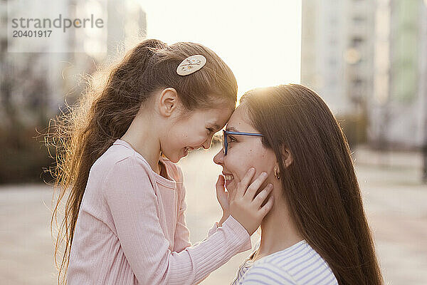 Happy girl touching forehead with mother