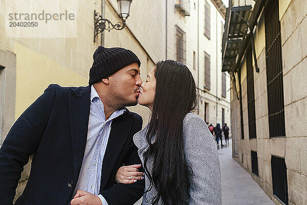 Romantic couple kissing amidst buildings