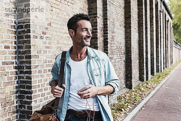 Smiling man with duffle bag walking at street