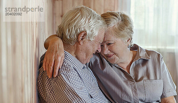 Elderly couple embracing each other at home