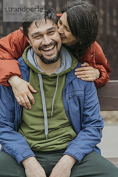 Smiling woman kissing man wearing jacket