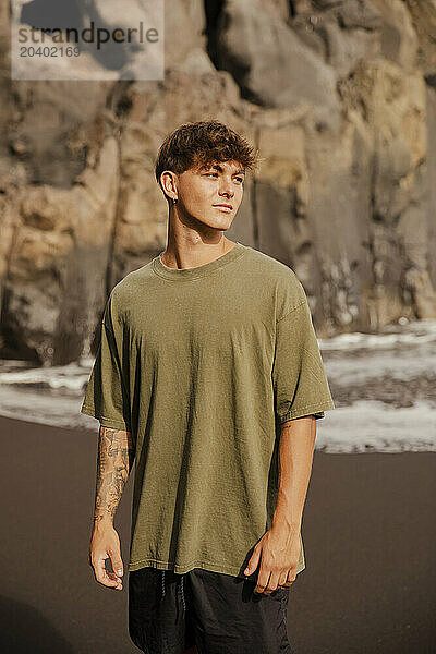 Handsome man in T-shirt standing at beach