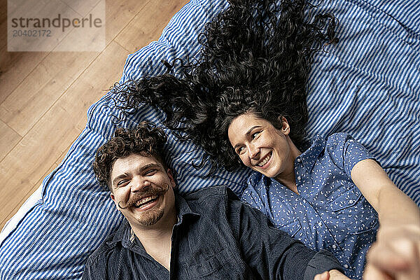Happy couple lying down on bed at home