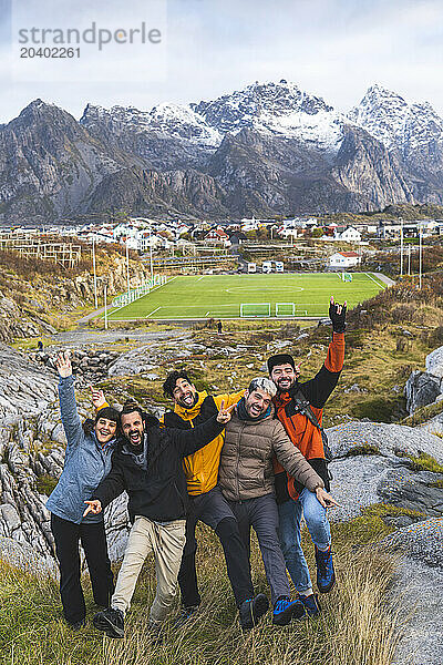 Norway  Northern Norway  Henningsvaer  Group of friends posing in Lofoten with soccer field in background