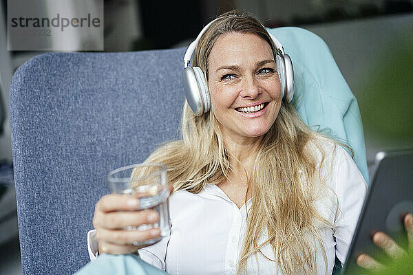 Happy relaxed businesswoman listening to music through wireless headphones at office