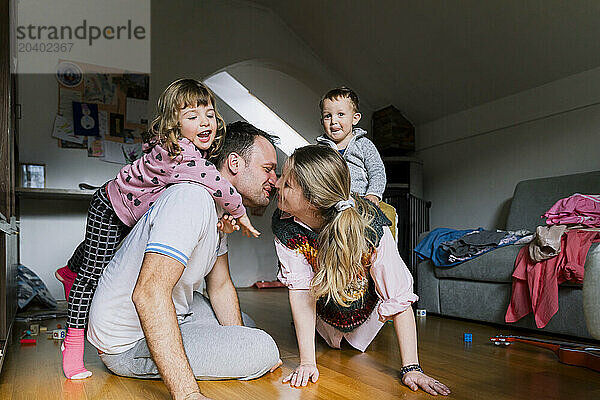 Parents with children playing in living room at home