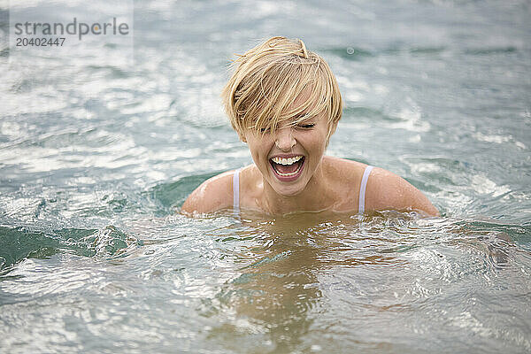 Happy young blond woman enjoying in lake