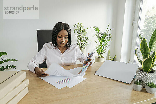 Businesswoman sorting documents sitting at desk in office