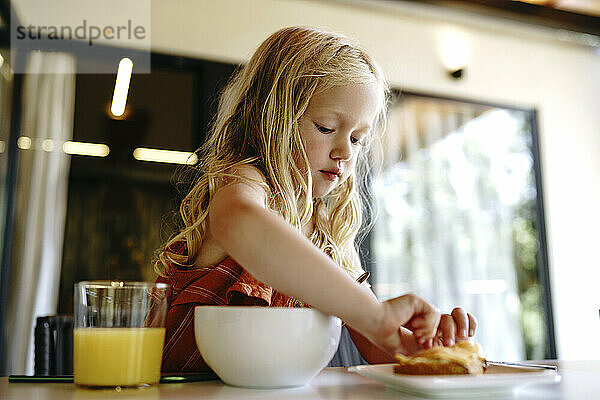 Blond girl preparing breakfast at table in apartment