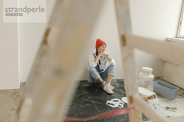 Woman taking break sitting in front of white wall at home