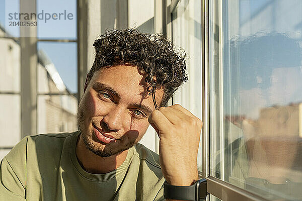 Smiling young man sitting near window