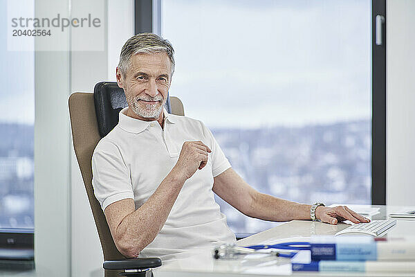 Portrait of confident doctor sitting at desk in medical practice