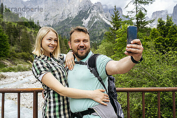 Happy man taking selfie with woman in front of Dolomites