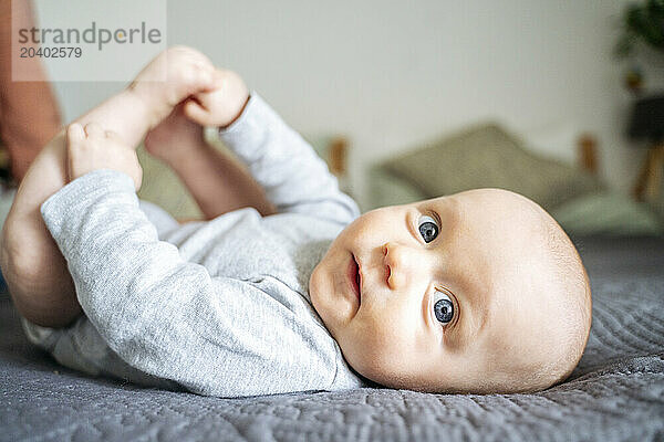 Cute baby boy lying on bed at home