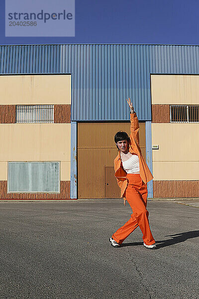 Woman dancing in front of building on sunny day