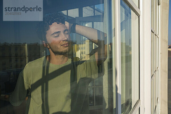 Smiling young man seen through glass on sunny day