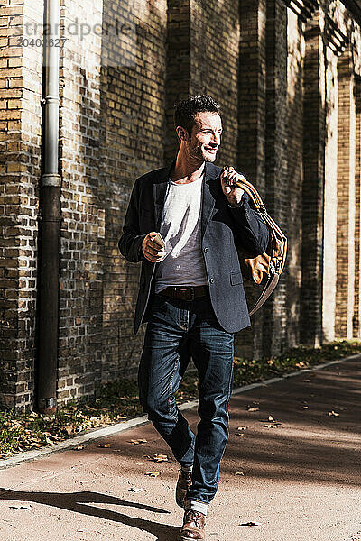 Handsome man walking on street at sunny day