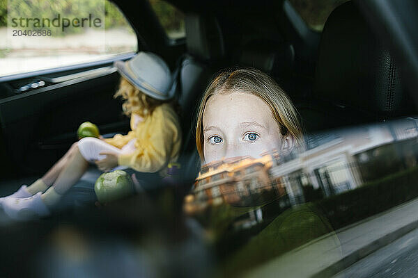 Curious girl looking through car window