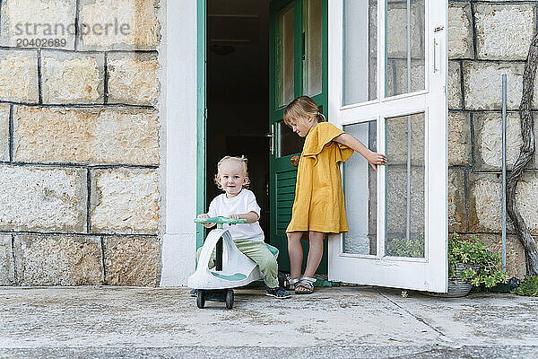 Siblings at doorway of house