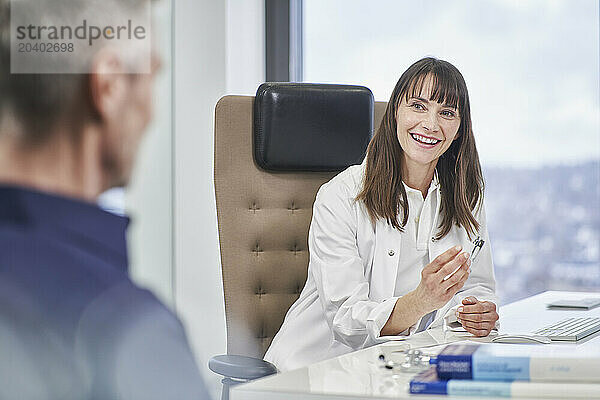 Smiling female doctor talking to senior patient in medical practice