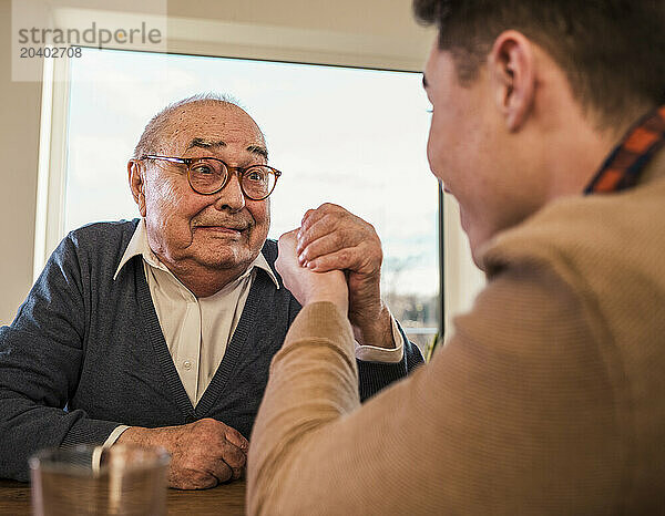 Senior man doing arm wrestling with grandson at home