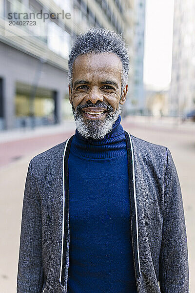 Smiling businessman standing in front of building