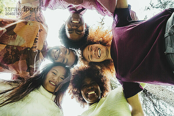 Happy multiracial friends huddling together at park