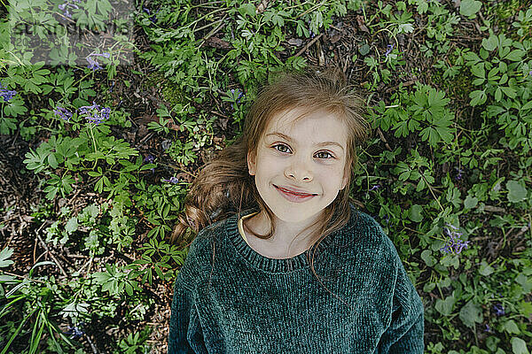 Smiling girl lying on grass in forest