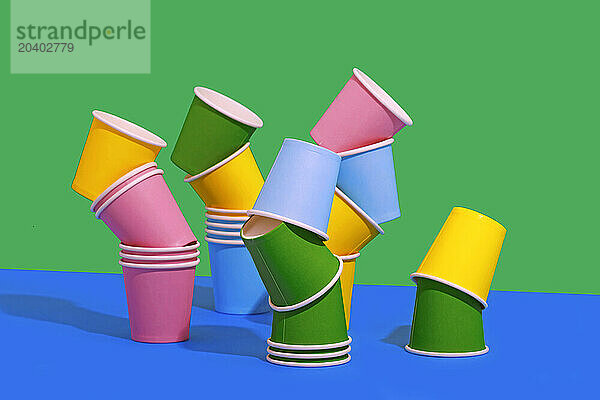 Multi colored disposable paper cups arranged against two tone colored background