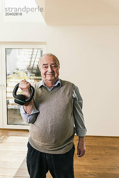 Smiling senior man exercising with kettlebell at nursing home