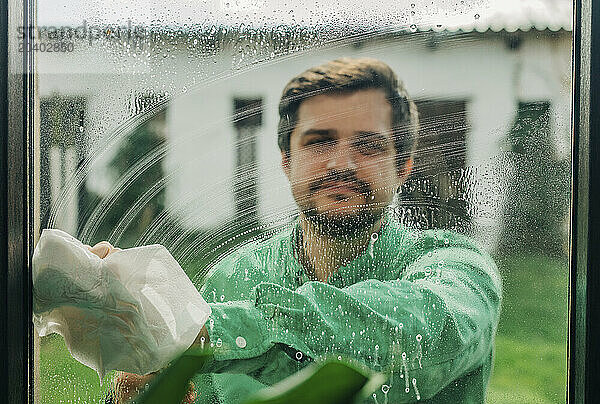 Man wiping soap sud from glass window