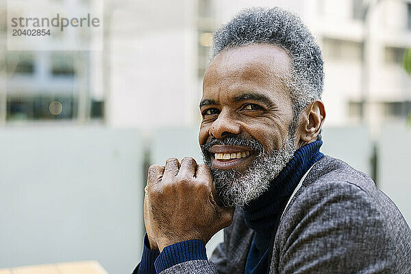 Smiling businessman with gray hair in front of buildings