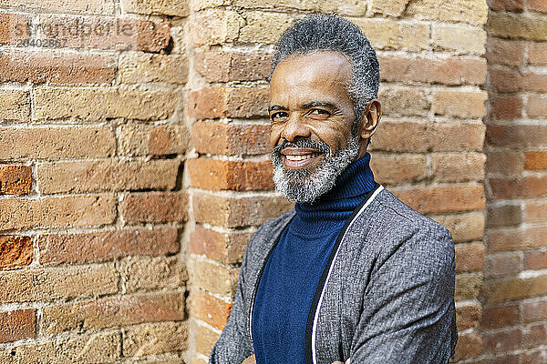 Smiling businessman standing near brick wall