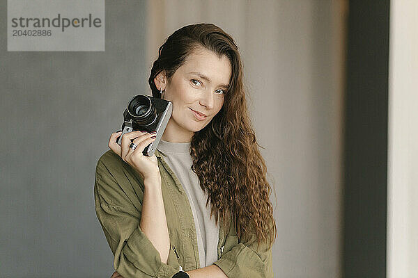 Smiling woman with camera in new home